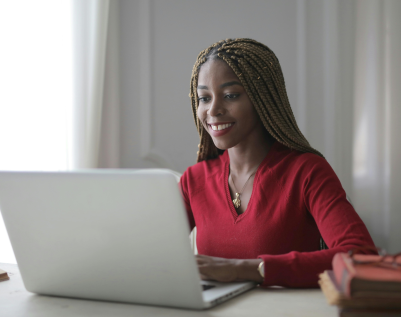 Young adult woman at her computer, learning essential English verbs with videos designed for adult beginners.